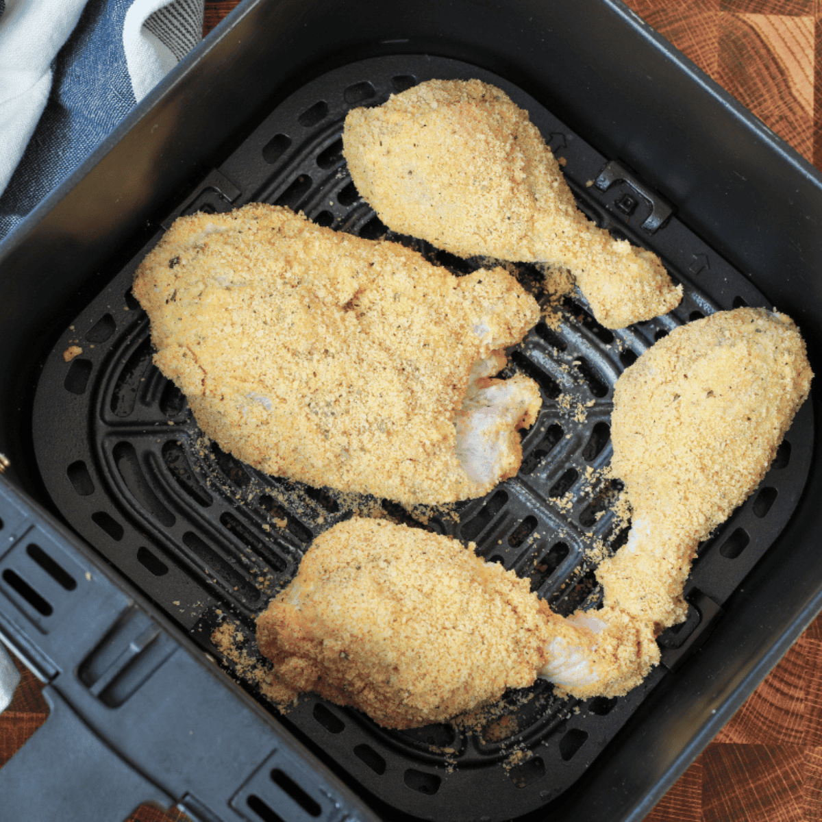 Coating chicken drumsticks in egg and pork rind mixture, then placing them in a single layer in the air fryer basket to cook until crispy