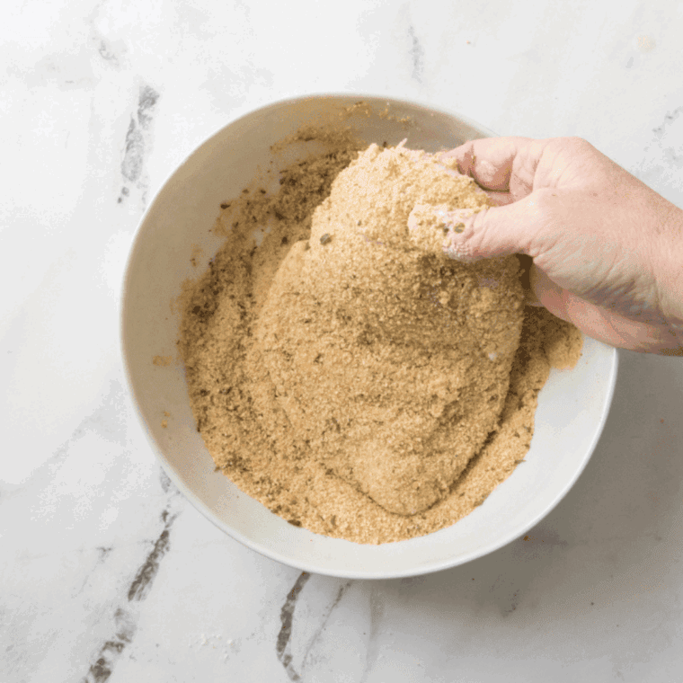 Preparing breading station with eggs, flour, seasonings, and Parmesan cheese in bowls.