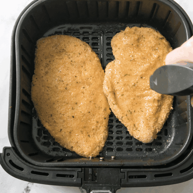 Coating chicken in egg and pork rind mixture before placing in air fryer basket.