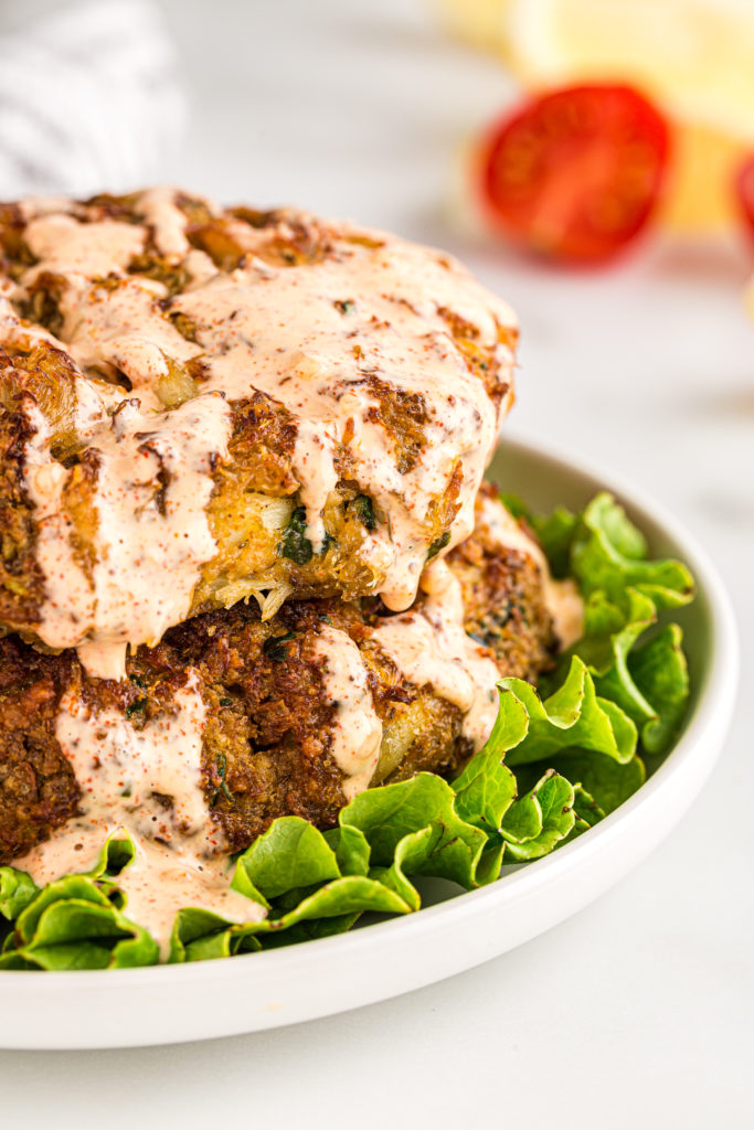 Golden brown air fryer crab cakes served on a plate, garnished with fresh herbs and accompanied by a dipping sauce.