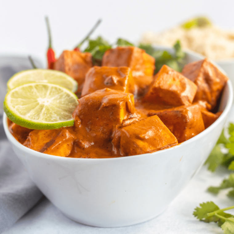 Plate of golden Air Fryer Curry Tofu garnished with fresh herbs.