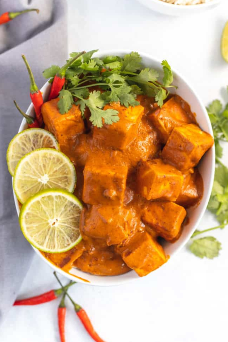 Plate of Air Fryer Curry Tofu with fresh herbs and slices of lemon on the side.