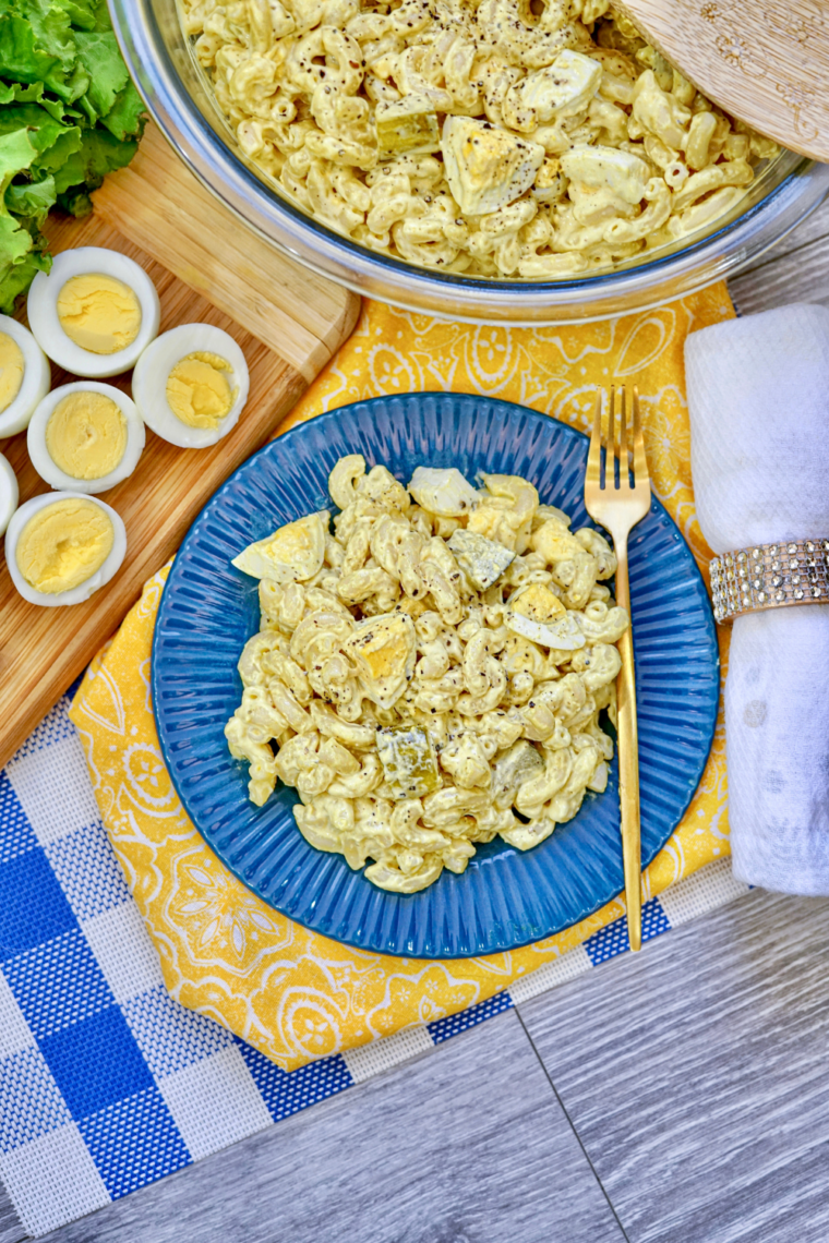 Creamy deviled egg pasta salad in bowl with macaroni, chopped eggs, pickles, and tangy mustard dressing mixed together.