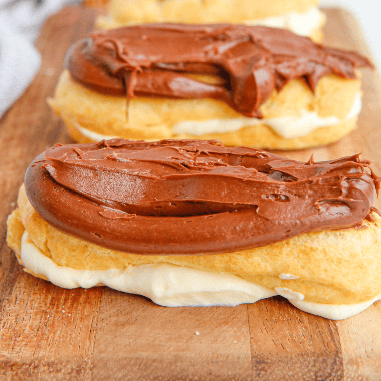 Golden and crisp homemade eclairs made in an air fryer, filled with creamy custard and topped with a glossy chocolate glaze.