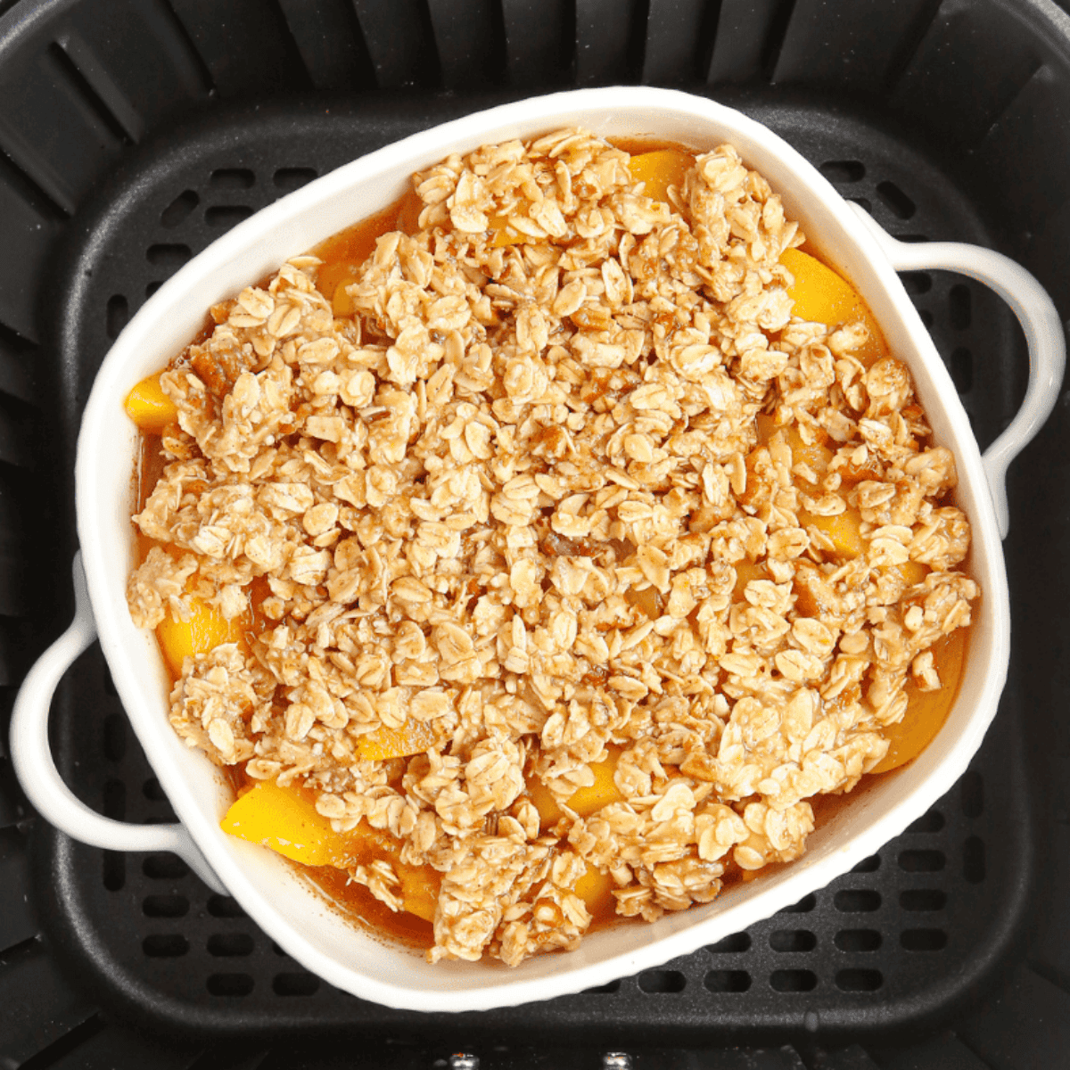 Air fryer set to 350°F, baking peach crumble until the topping is golden brown and peaches are hot and bubbly.