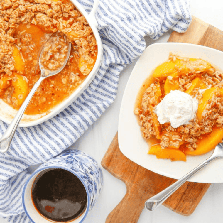 Golden brown Air Fryer Peach Crumble served warm in a white dish with a scoop of vanilla ice cream on top.
