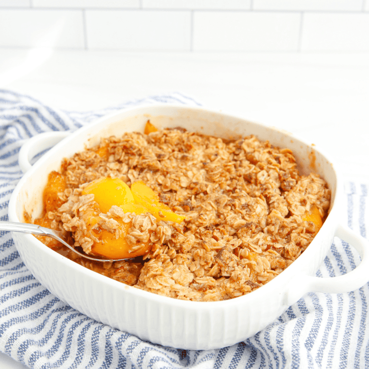 Warm Air Fryer Peach Crumble with golden oat topping served in a dish, topped with melting vanilla ice cream.