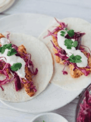Close-up of homemade Blackened Baja Fish Tacos with crispy seasoned fish, fresh slaw, and zesty sauce on tortillas.