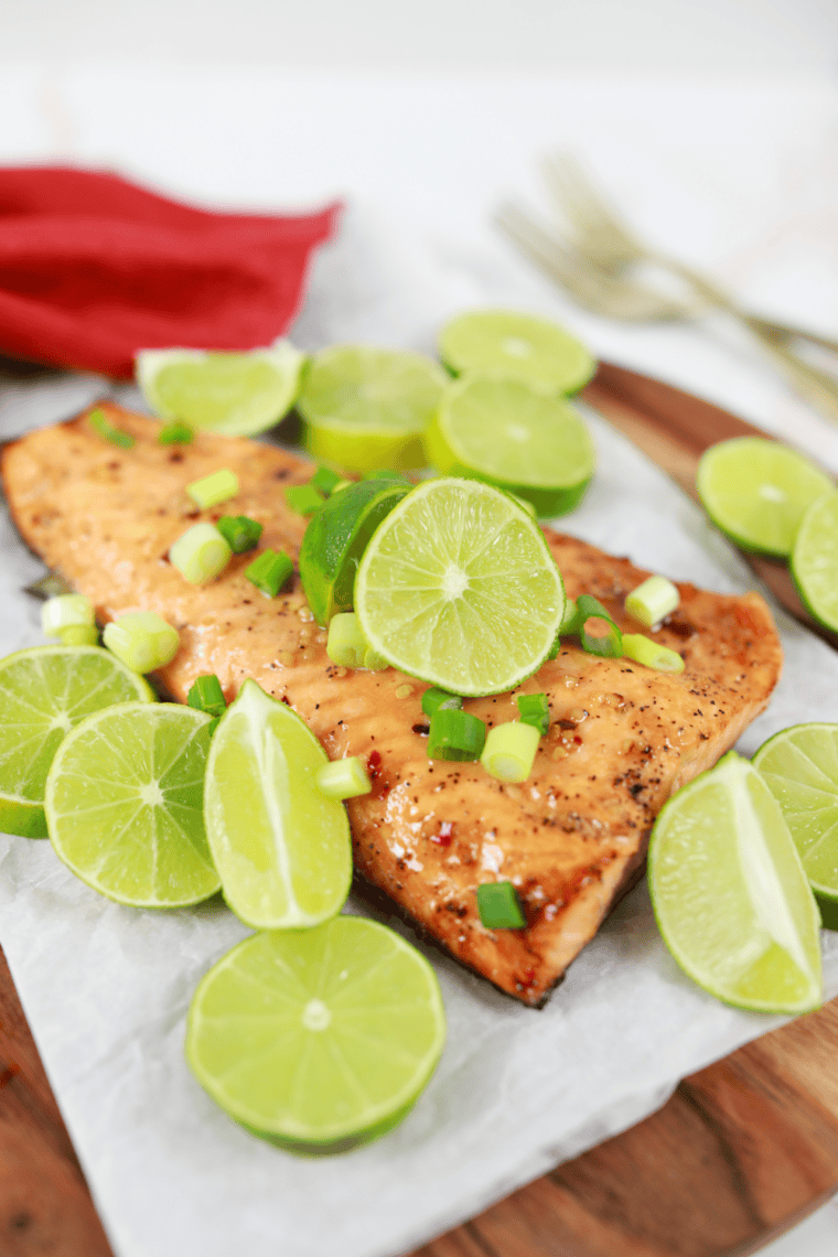 Cedar plank salmon fillets with maple bourbon glaze and cherry gastrique, garnished with parsley and orange zest, ready to serve.