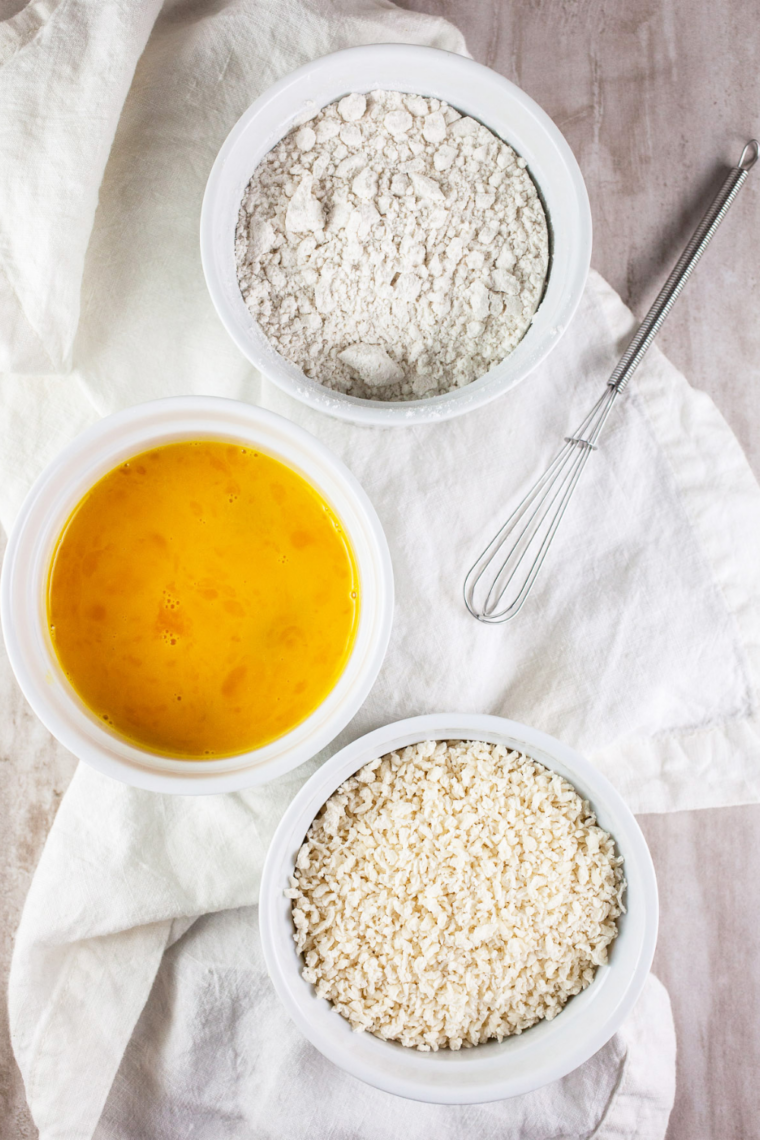 Shrimp coated in seasoned flour mixture resting in a bowl in the refrigerator.