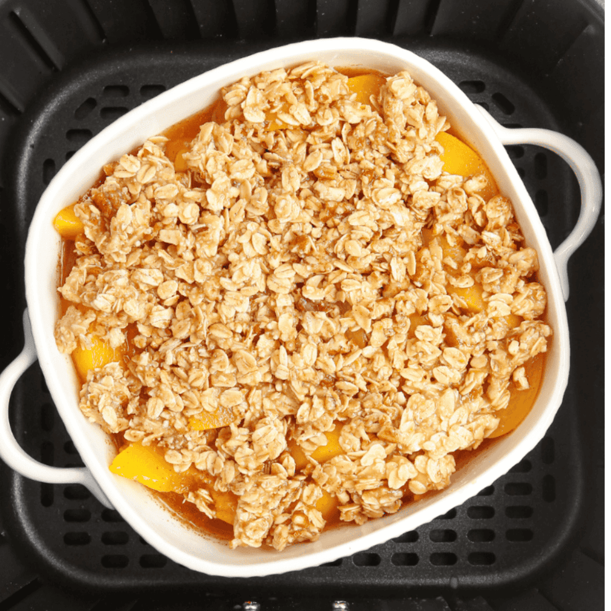 Air fryer set to 350°F, baking peach crumble until the topping is golden brown and peaches are hot and bubbly.
