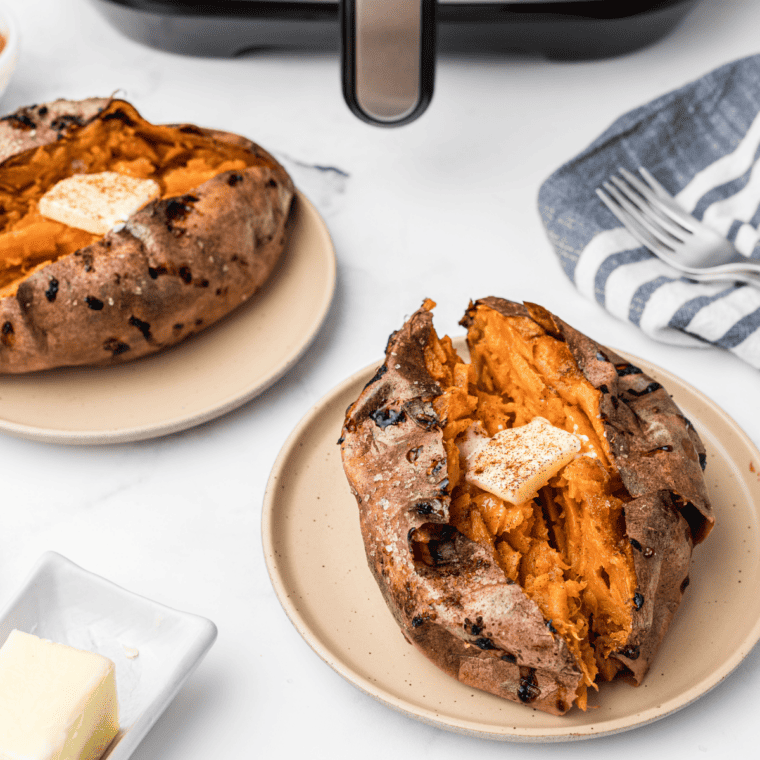 Reheated sweet potato split open with crisp skin and a fluffy center, butter melting on top