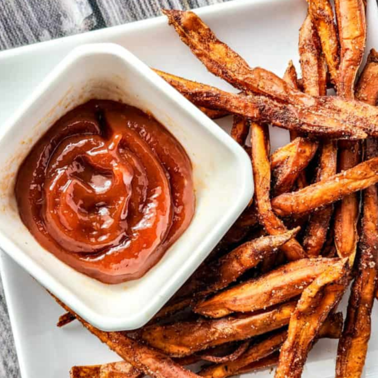 erving crispy spicy air fryer sweet potato fries with a side of dipping sauce."