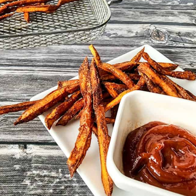 Plate of Spicy Air Fryer Sweet Potato Fries, with a side of ketchup.