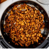 Bowl of honey roasted walnuts crisping in an air fryer basket