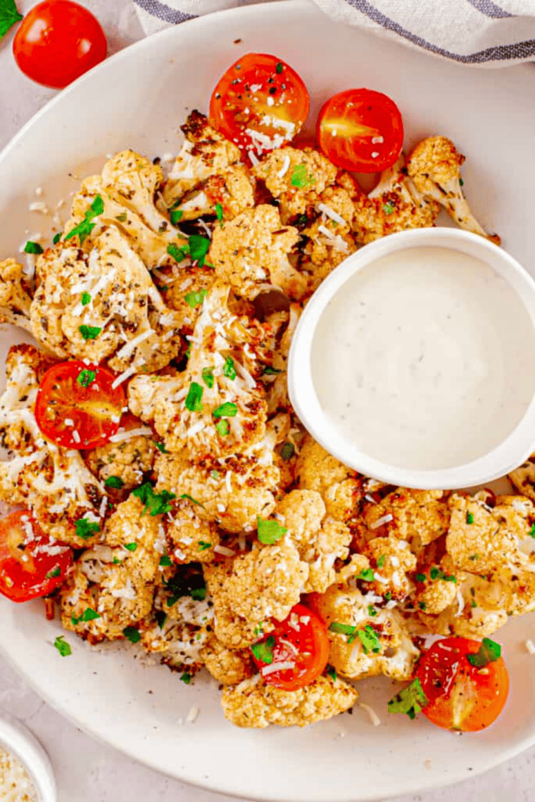 Golden air fryer cauliflower florets served with roasted, caramelized tomatoes in a bowl.
