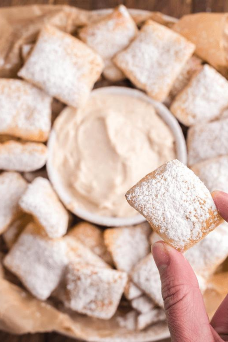 "Finished Air Fryer Cinnastix on a white plate, ready to be served with a side of icing for dipping."