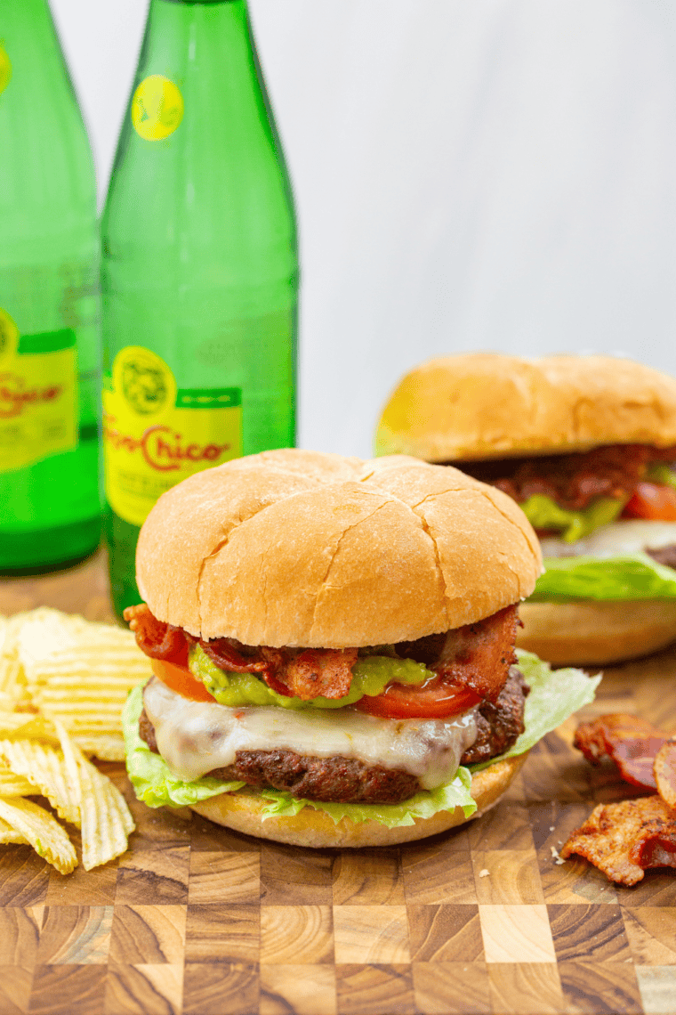 Air fryer burger with crispy bacon, melted cheese, and creamy guacamole on a toasted bun.