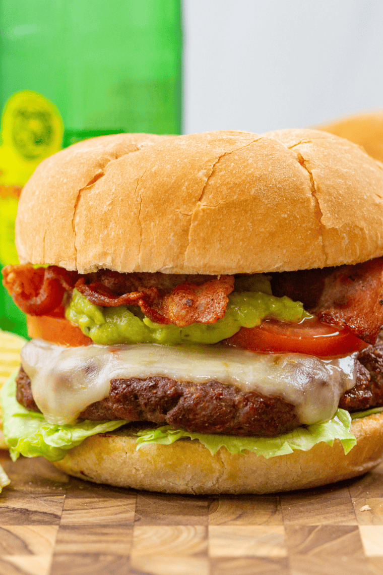Air fryer burger with crispy bacon, melted cheese, and creamy guacamole on a toasted bun.