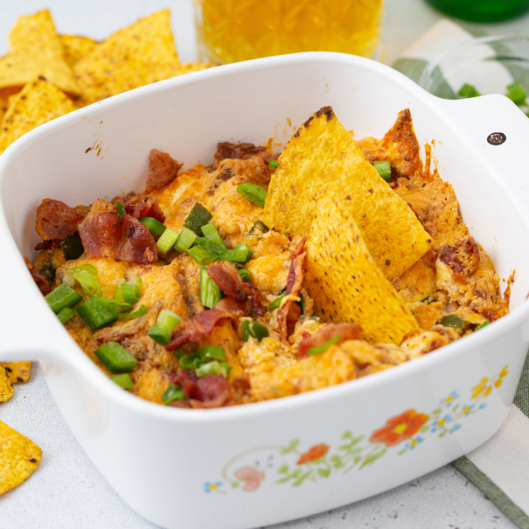 Bowl of air fryer jalapeño popper dip with tortilla chips and a beer, a game day appetizer spread