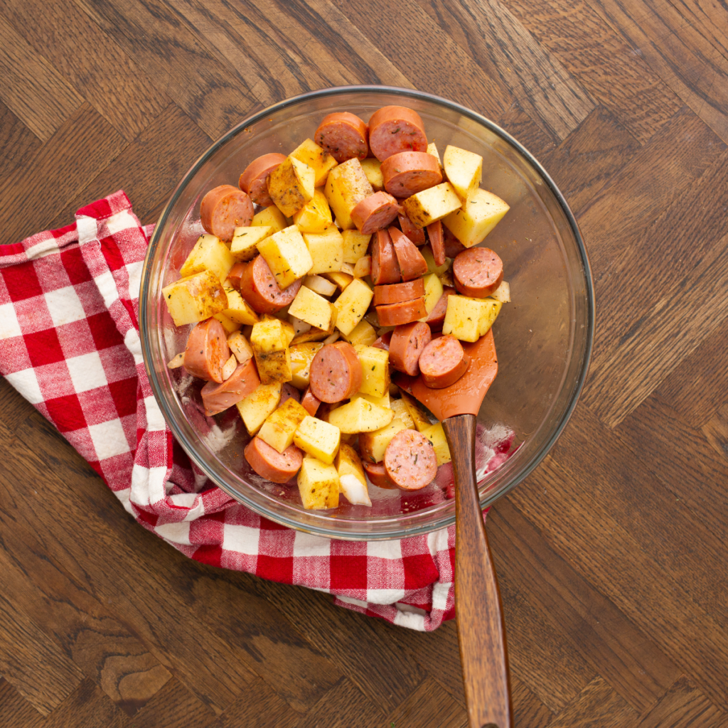 Air Fryer Kielbasa and Potatoes mixture being mixed in a bowl. 