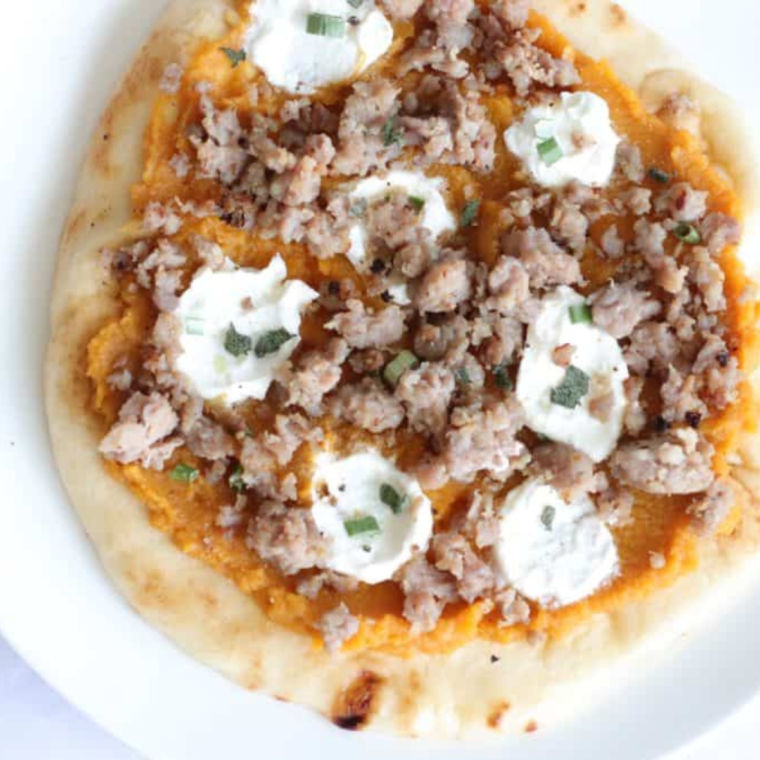 Topping the pumpkin and ricotta pizza with chives, salt, black pepper, cooked sausage, and chopped sage before air frying.