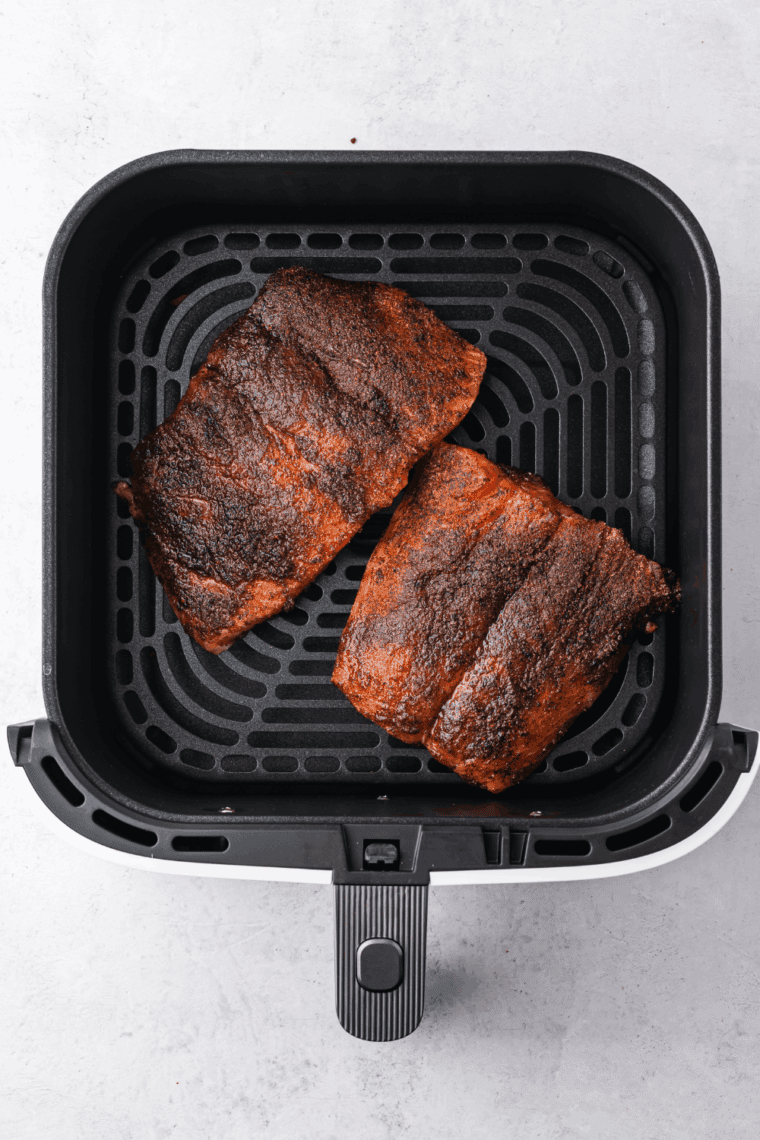 Salmon fillets cooking in air fryer basket until golden and flaky