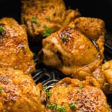 Air Fryer Chili Lime Chicken Thighs served on a plate with lime wedges and fresh cilantro.