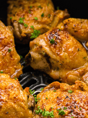 Air Fryer Chili Lime Chicken Thighs served on a plate with lime wedges and fresh cilantro.