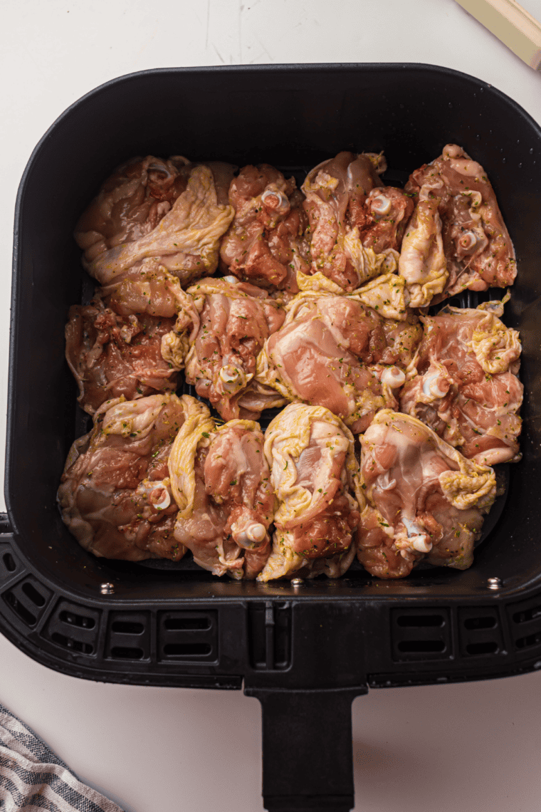 Chicken thighs in air fryer basket, skin-side down, golden and crispy.