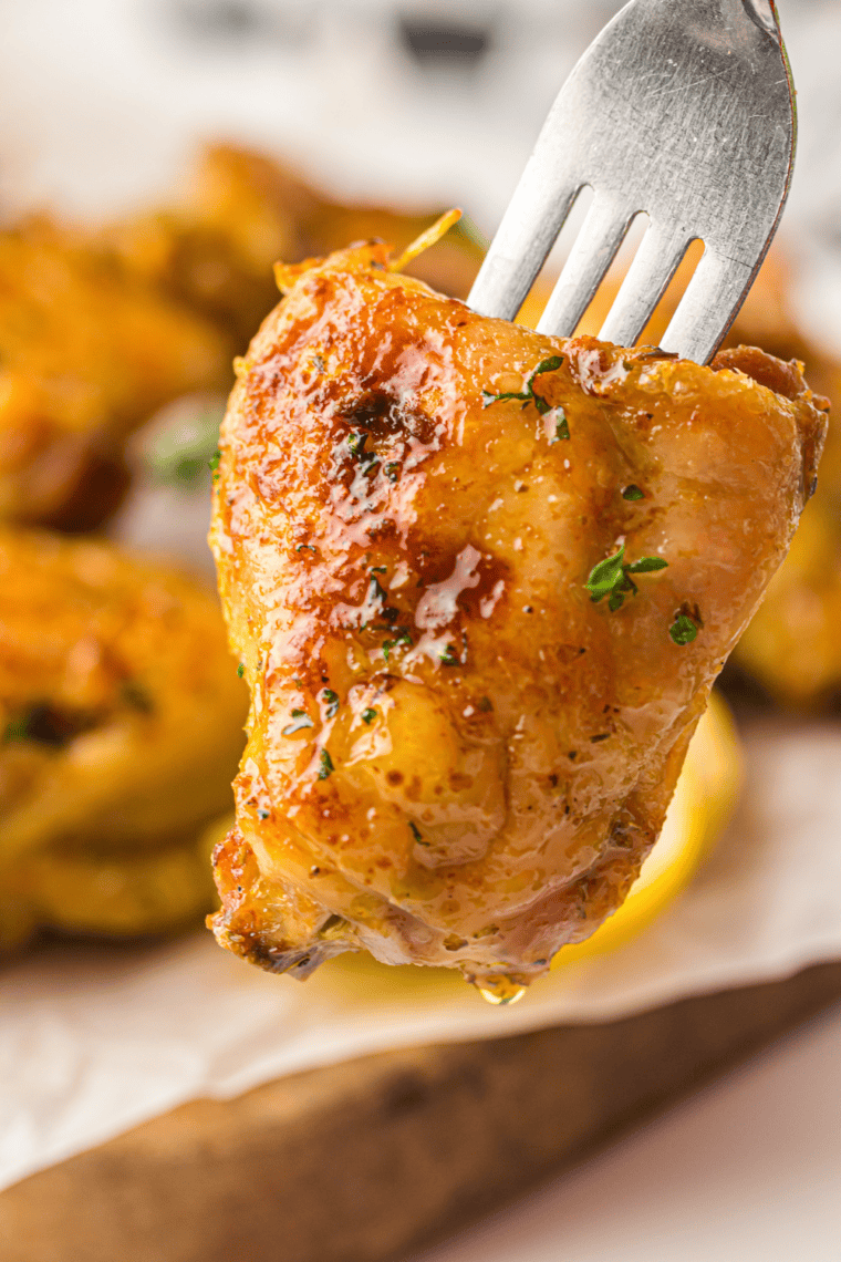 Golden crispy Air Fryer Chili Lime Chicken Thighs garnished with fresh cilantro and lime wedges, served in a white dish.
