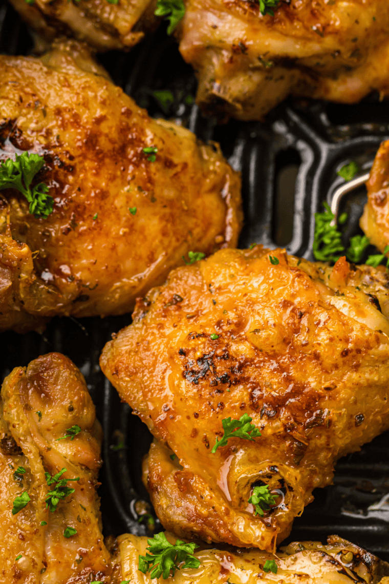 Crispy Air Fryer Chili Lime Chicken Thighs garnished with chopped cilantro and lime wedges on a serving plate.