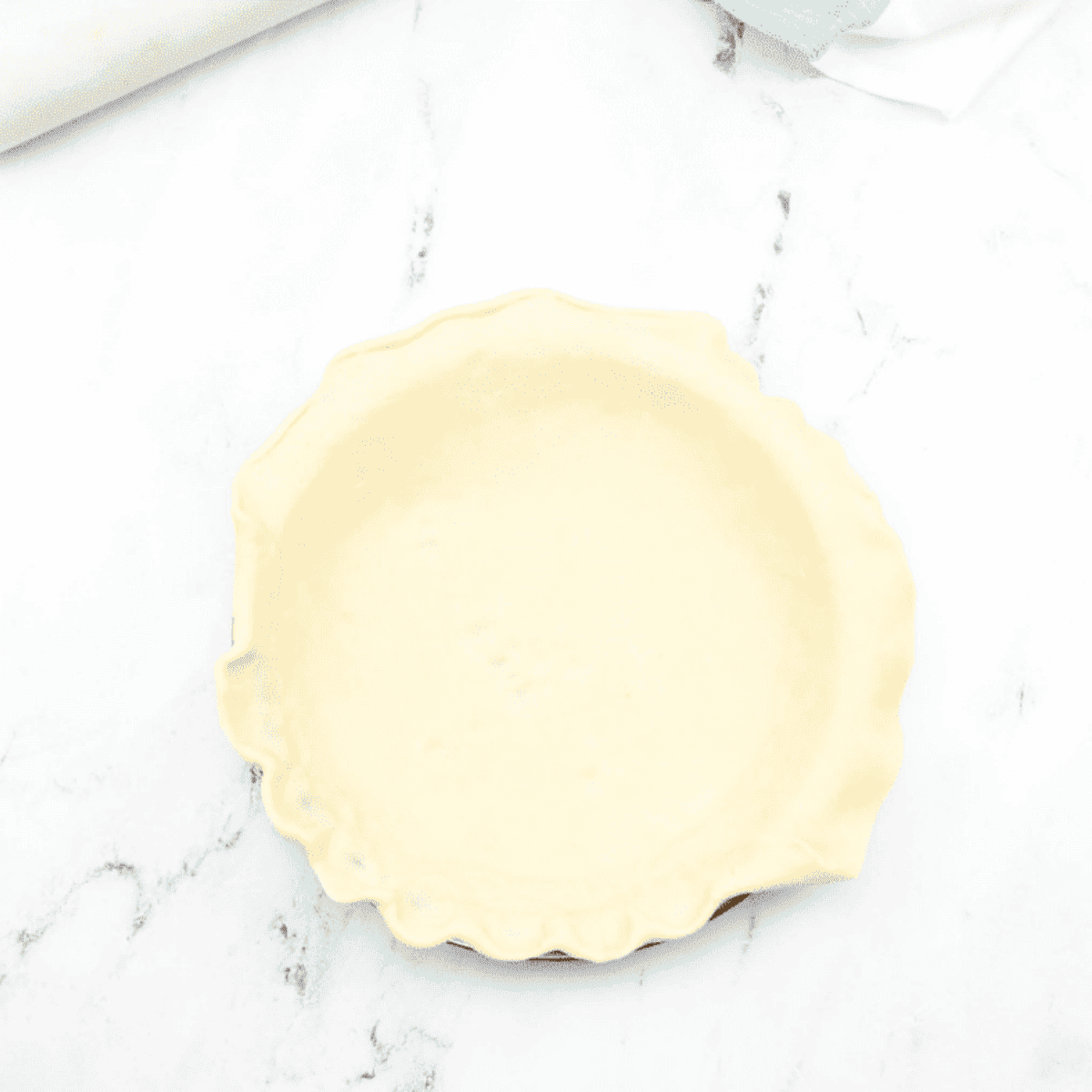 Rolling out pie crust, placing it in an air fryer-safe pan, and pre-baking until golden brown at 320°F.