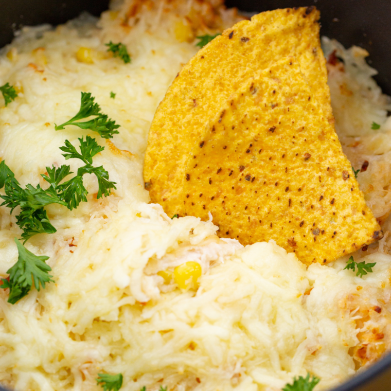 Air fryer white chicken chili dip topped with melted cheddar and mozzarella, garnished with cilantro