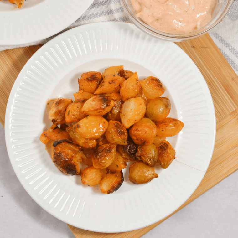 Golden brown pearl onions cooked in the air fryer, served in a white bowl.