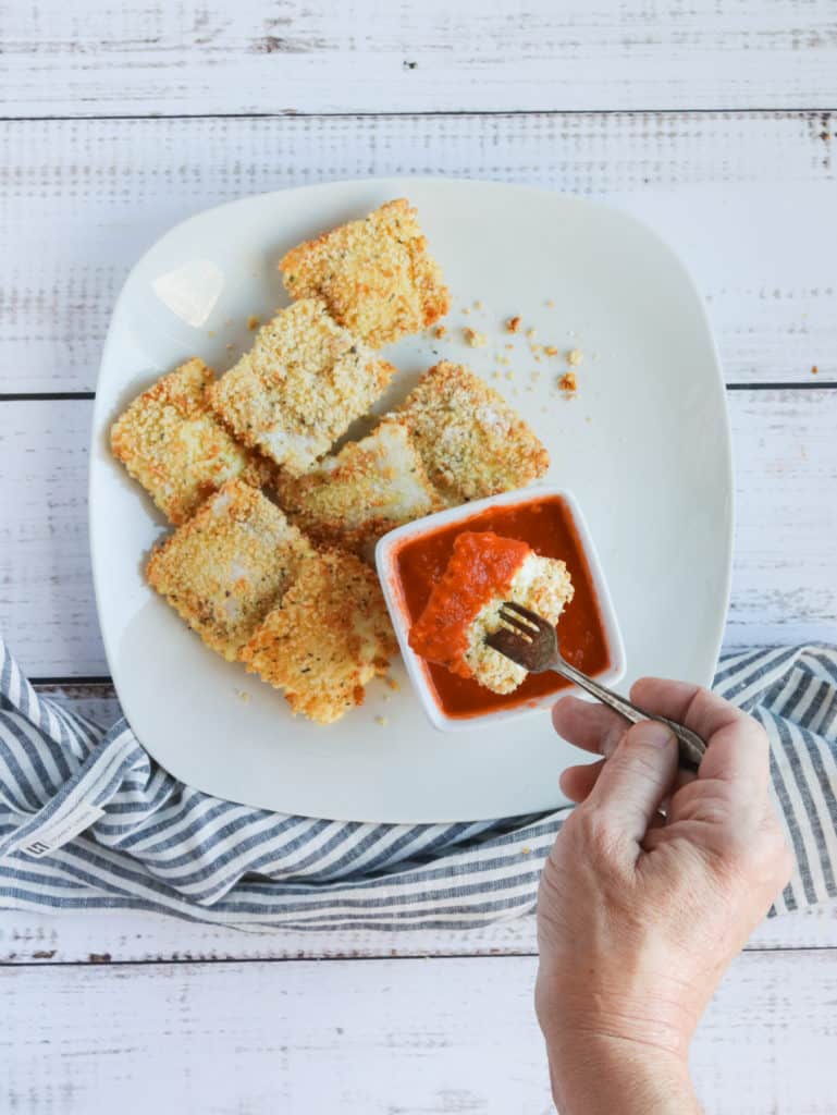 Can I Make Air Fryer Frozen Toasted Ravioli In The Oven?
Yes, prepare them, and then instead of putting them into the air fryer, place them into a preheated 400 degrees F for 12-15 minutes.

Making them in the oven is an excellent idea if you make a massive batch of them for a party or get-together.

Can I Make Use Fresh Ravioli?
Yes, change the air frying time to about 3-5 minutes, as they will cook faster than the frozen ones.

Next time you are at the store, look around in both the freezer section and the grocery store’s refrigerator section. You will be amazed at all of the different varieties now available.

What Are Some Dips To Go With Air Fried Raviolis?
Here are some of my favorites,

Alfredo sauce
Ranch Dressing
Pesto Sauce
Marinara Sauce (A Great Recipe for the Instant Pot Homemade Marinara Sauce)
Any sauce you like will be a great dipping sauce, even if you want to add some garlic and melted butter in a small saucepan.



Optional toppings: Grated Parmesan cheese, or mozzarella cheese, and fresh herbs!

Can I Use Filled Ravilois With Meat?
Yes, you can use whatever stuffed ravioli you would like. I often change between cheese and meat.

There are so many different varieties now available in the supermarket. Whether fresh or frozen, they are excellent in the air fryer.

How Long To Cook Frozen Toasted Ravioli In Air Fryer
Add the frozen ravioli to the air fryer basket; a d then set the temperature to 350 degrees F for 6 minutes. Make sure they are fully cooked before you remove them from your air fryer basket.



How To Cook Frozen Louisa Toasted Ravioli In Air Fryer
Place the frozen ravioli in the air fryer basket, and then spray with olive oil, or brush with vegetable oil.  Set the temperature to 350 degrees F, air fryer setting, and air fry for about 5-7 minutes.

What If My Breaded Ravioli Looks Dry?
This is a great recipe, and with a few sprays of olive oil, it will come out perfectly toasted and never dry. If it does come out dry, reduce the temperature, and spray halfway with olive oil (or cooking spray)

How To Reheat Ravioli in Air Fryer
If you have any leftover toasted ravioli, add them to the air fryer basket, and then spray them with olive oil.

Air fry for about 3-4 minutes, at 380 degrees F, until the toasted ravioli is heated through.

How To Reheat Frozen Toasted Ravioli In the Air Fryer
Now that they have frozen air fryer toasted ravioli products to make them, they are already breaded for you.

You can toss them into the air fryer and then set the temperate to 350 degrees F and air fry for about 3-5 minutes.

Some of the ones I have tried at Pioneer Woman’s that come in the freezer have been found at Costco and my local grocery store. (Both in the freezer section)

Can You Freeze Air Fryer Fried Raviolis?
Yes. Just bring them to room temperature, then place them into a Ziploc bag, or an airtight container, and store them for up to 2 months.

To Reheat From Frozen: Set them into your air fryer at 350 degrees F and cook time for 8 minutes, flipping halfway.

More Air Fryer Recipes:
EASY AIR FRYER, CRISPY RED-PEPPER JELLY WINGS
AIR FRYER, FRIED SALAMI CHIPS (KETO FRIENDLY)
AIR FRYER BOSTON BROWN BREAD
HOW TO MAKE FROZEN HAMBURGERS IN THE AIR FRYER
Air Fryer Southwest Egg Rolls
Air Fryer Crispy Chicken Wings
Air Fryer Olive Garden Chicken Parmesan
If you have been looking for a new air fryer ravioli recipe or new favorite appetizers, I hope that you will try this, remember to leave a star rating after trying this recipe!

