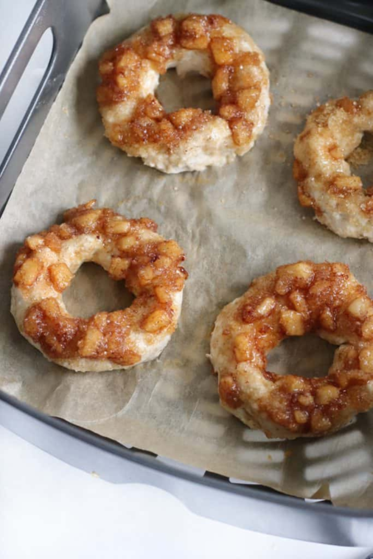 Freshly prepared apple cinnamon bagels in the air fryer tray, showcasing their pre-cooked appearance