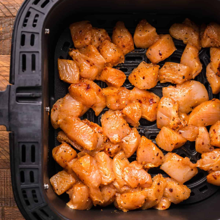 Coating chicken bites in breadcrumbs before placing them in the air fryer.