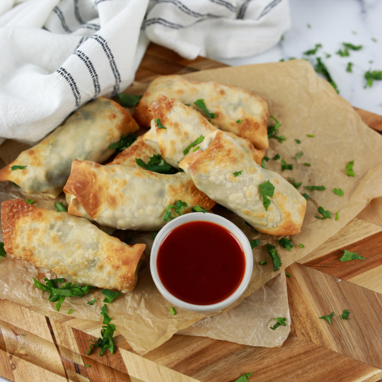 Golden, crispy Air Fryer Chicken Cilantro Egg Rolls filled with seasoned chicken and fresh cilantro, served with a side of dipping sauce.