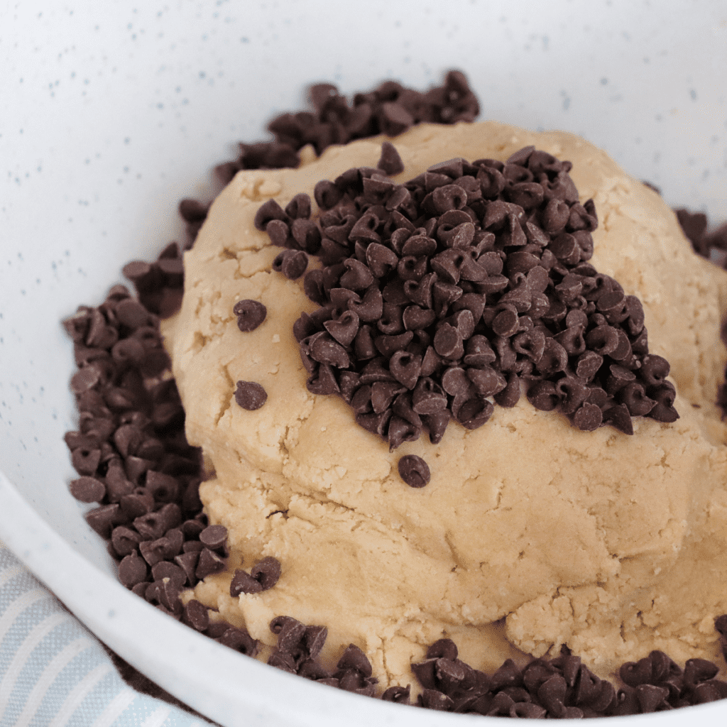  Cookie dough resting at room temperature beside an air fryer preheating to 315°F, with parchment paper lining the basket and greased muffin rings ready for use.