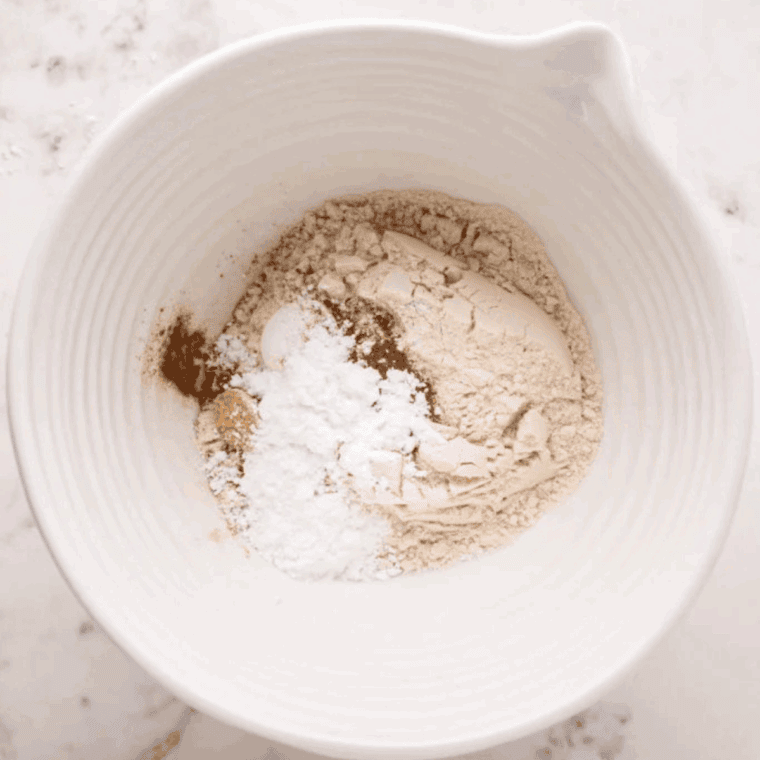 Mixing flour, baking powder, salt, sugar, cinnamon, and powdered sugar in a bowl, then whisking in maple extract, sour cream, egg, and melted butter.
