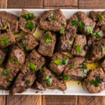 Juicy steak bites tossed in garlic butter sauce, freshly cooked in an air fryer with a crisp seared exterior.