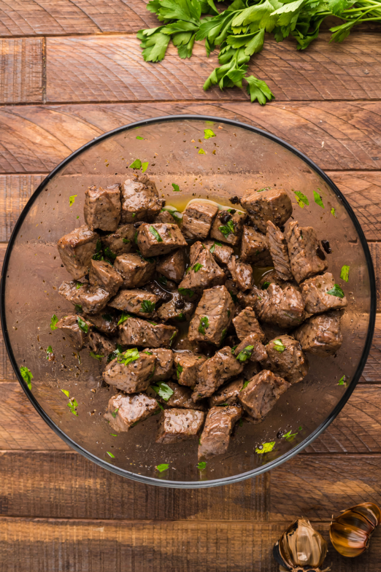 Air fried steak bites tossed in a warm skillet with garlic butter, coating each piece evenly for rich flavor.