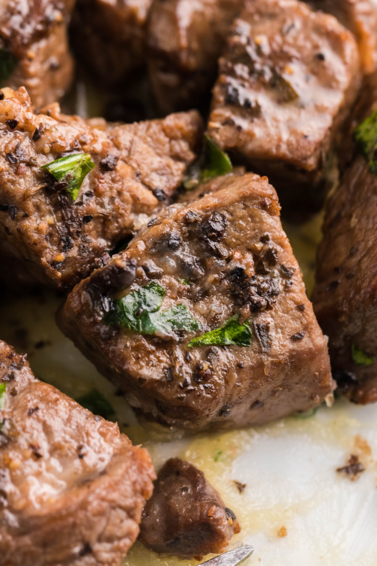 Crispy seared steak bites tossed in garlic butter sauce inside an air fryer basket, golden brown and juicy.