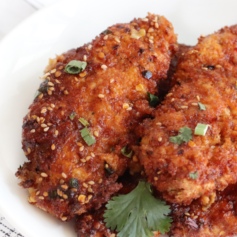 Plate of crispy Air Fryer Korean Sticky Chicken Fingers with sesame seeds and chives"