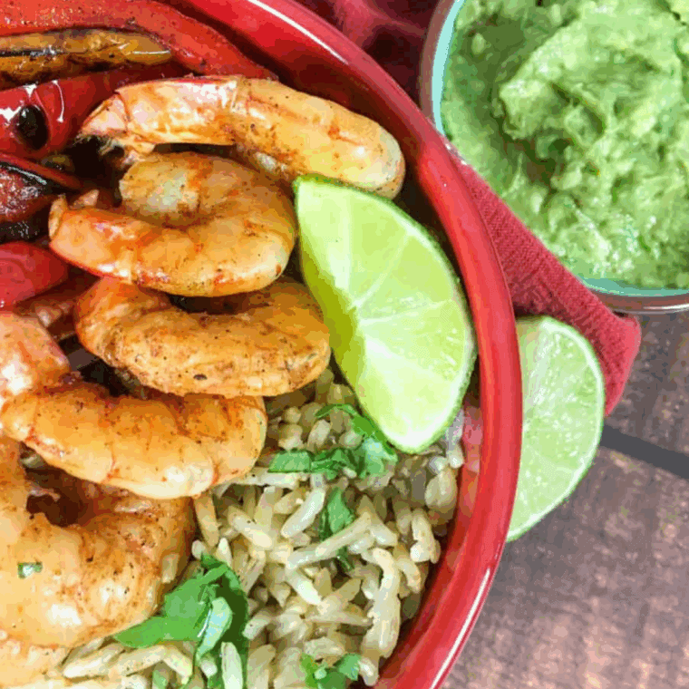 Air fryer shrimp fajita bowl with seasoned shrimp, colorful peppers, onions, and rice topped with fresh lime and cilantro.