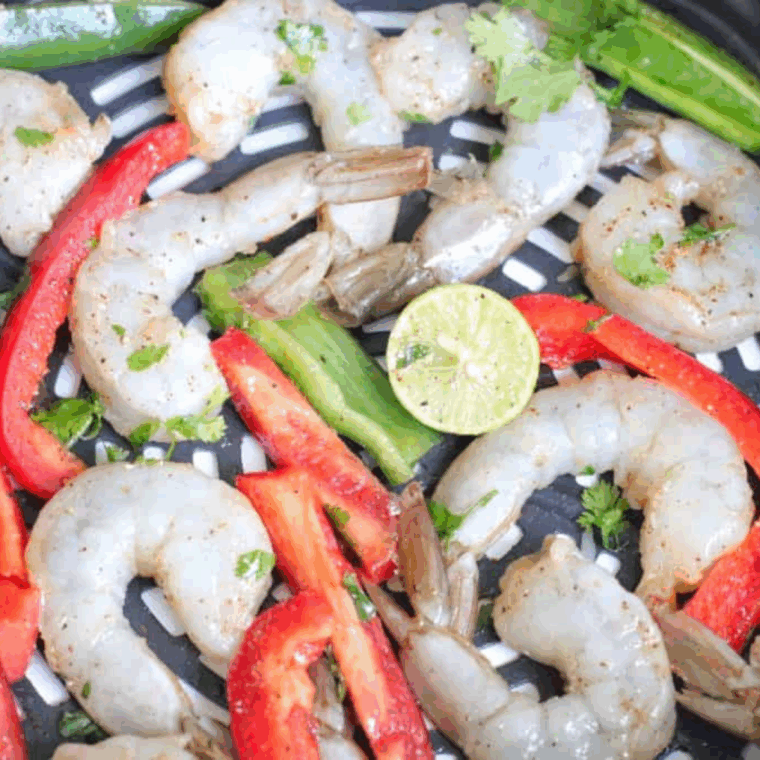 Seasoned shrimp with spices and oil in an air fryer basket, cooking at 400°F until pink, opaque, and perfectly tender.