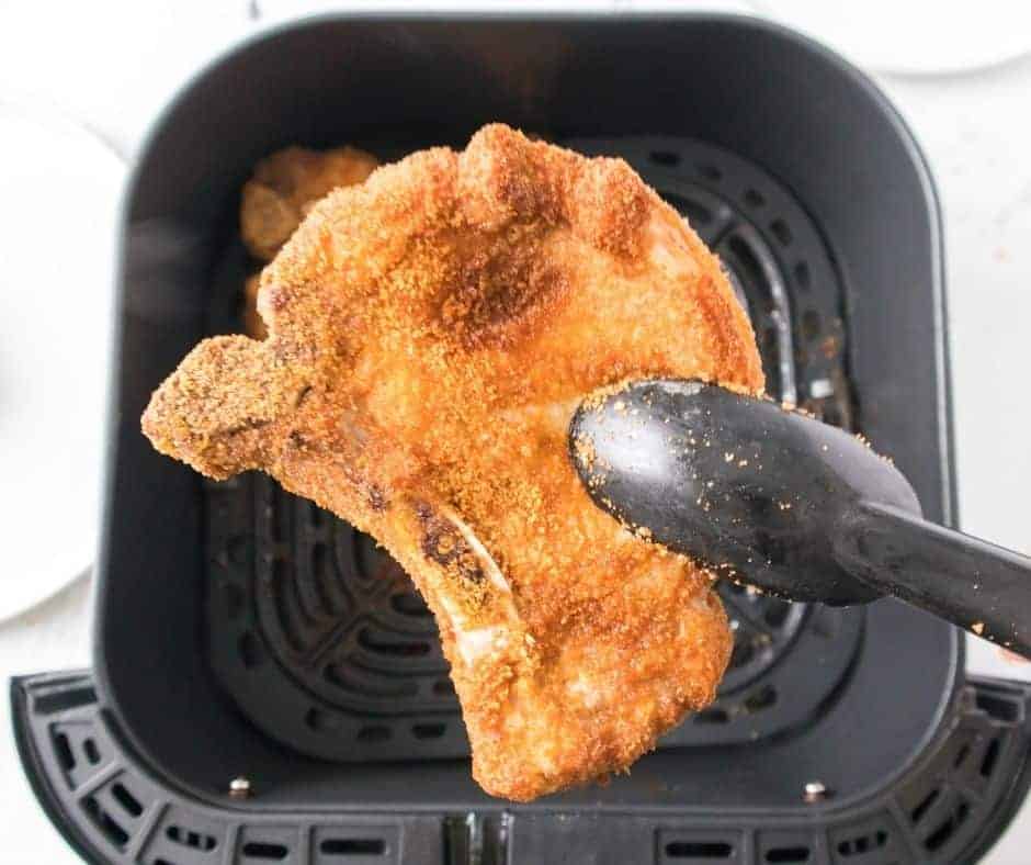 Air fryer breaded pork chops with the air fryer basket visible in the background.