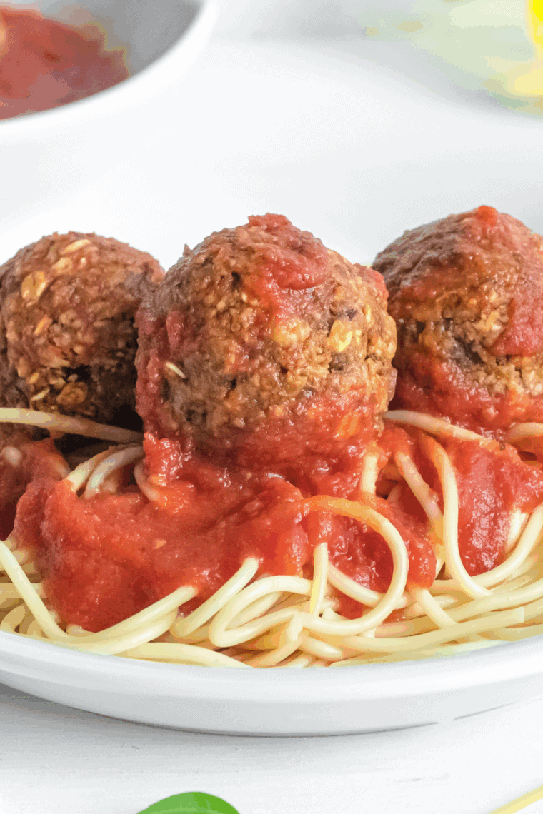 Golden-brown air fryer vegan meatballs served on a plate with marinara sauce and fresh herbs