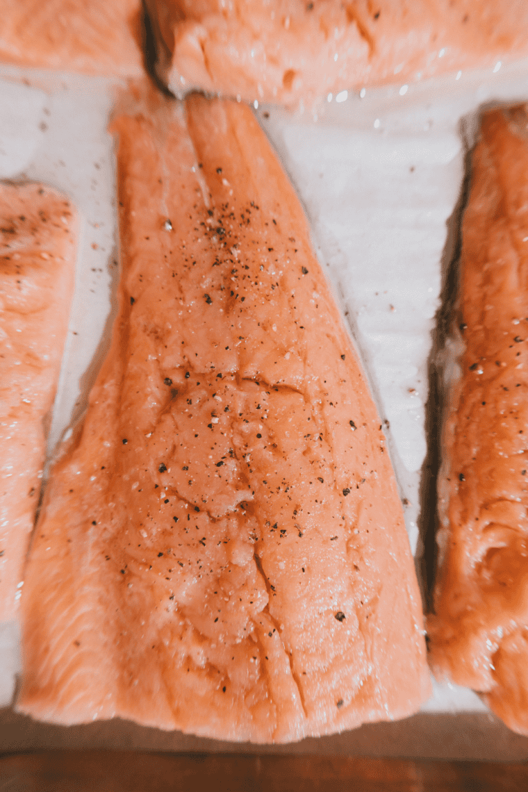 salmon fillets being patted dry with paper towel and brushed with olive oil